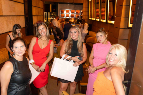 Group of women at an indoor party, showcasing hairstyles styled with a gold hair wax stick (sparkling, party-ready looks).