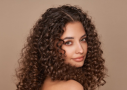 A woman with smooth, defined curls, showcasing the frizz-free, polished results a hair wax stick delivers for curly hair.